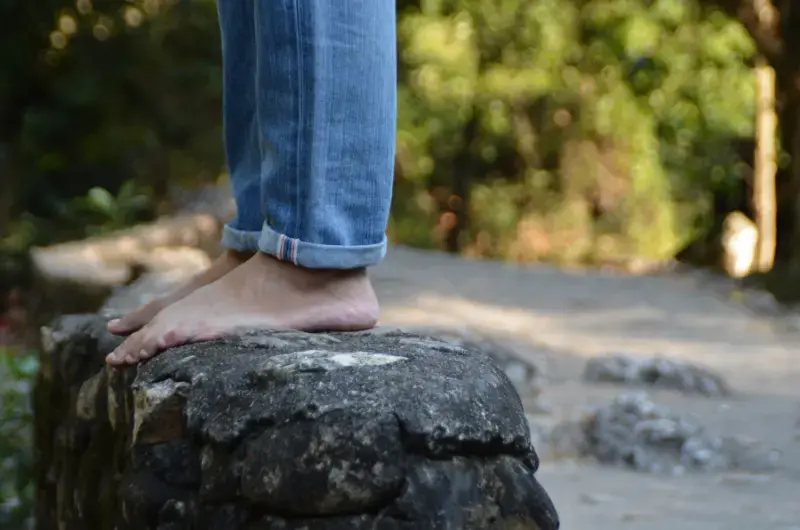 Man standing barefoot on a rock, showing balance and foot awareness on a natural surface