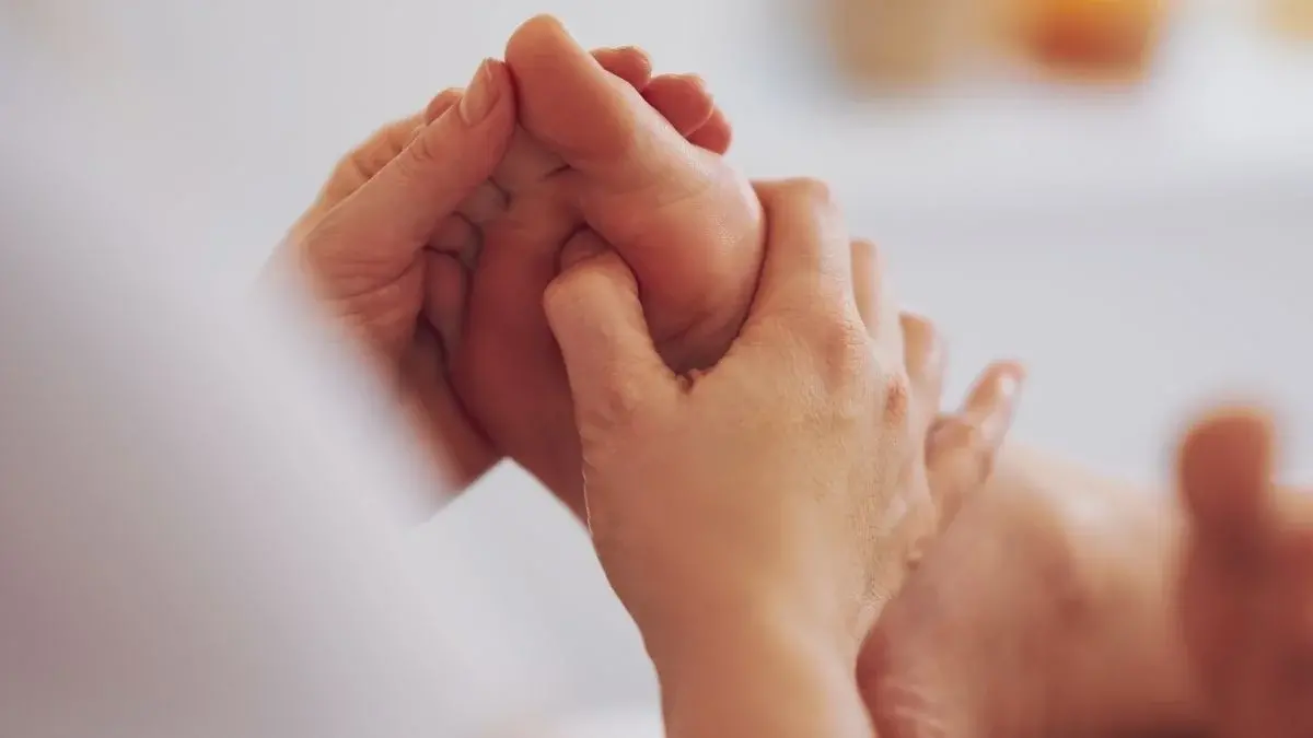 Applying pressure to the sole of the foot during a reflexology session