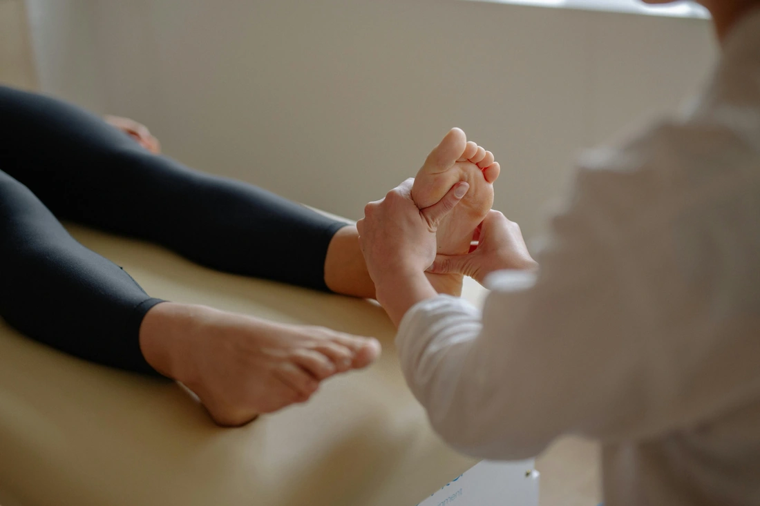 Hands applying focused pressure to the sole of the foot during a reflexology session